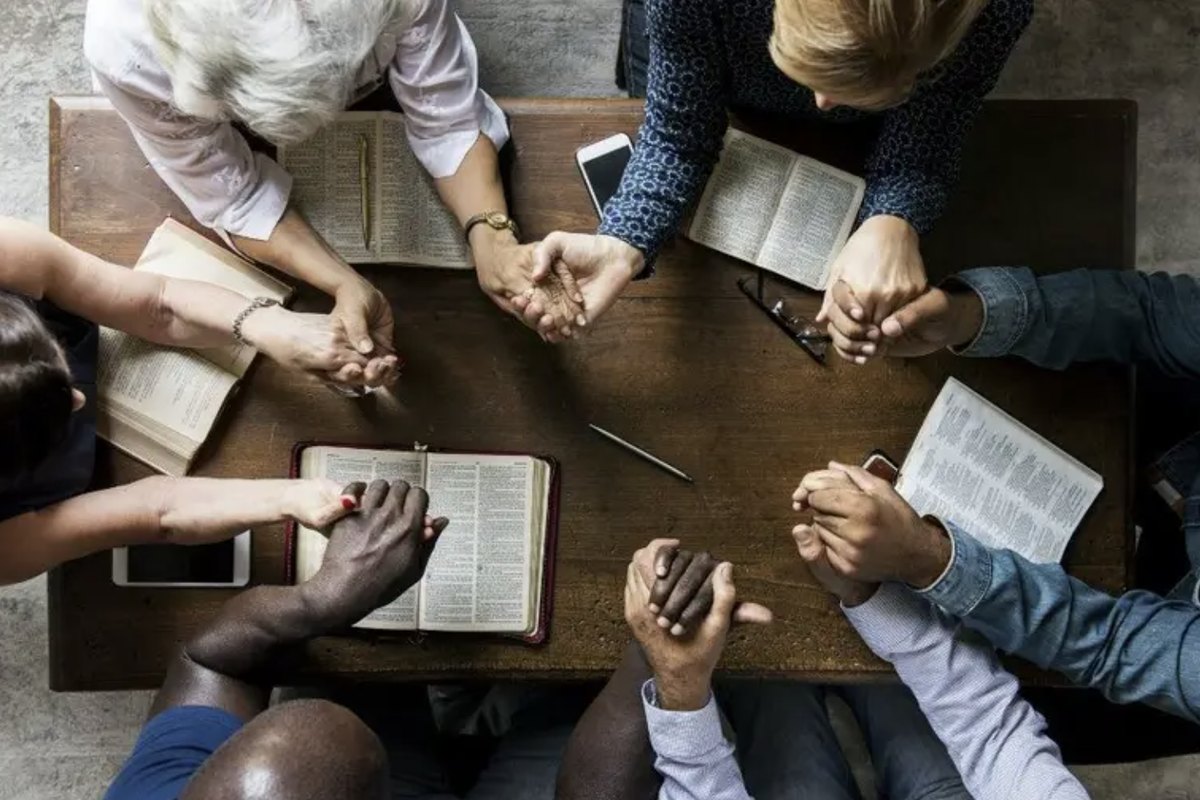 Diverse leaders praying together around an open Bible